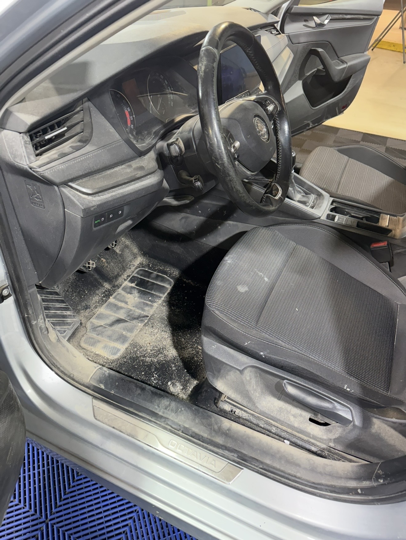Stark verschmutzter Fahrerfussraum und staubiges Armaturenbrett vor der Innenreinigung.